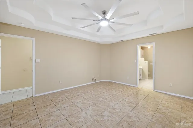an empty room with chandelier fan and windows