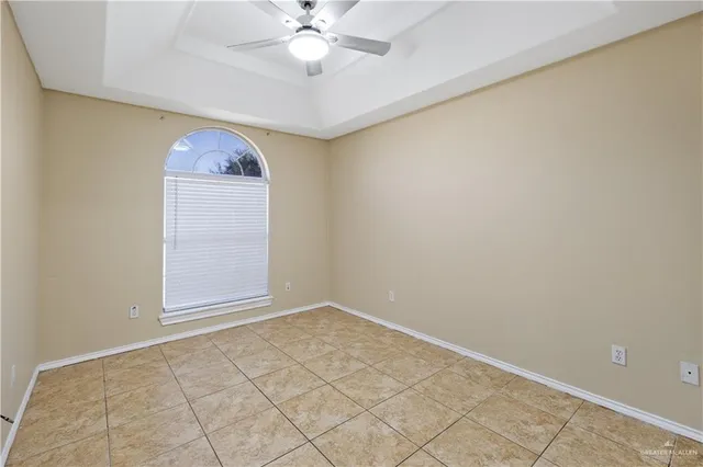 an empty room with a chandelier fan and windows