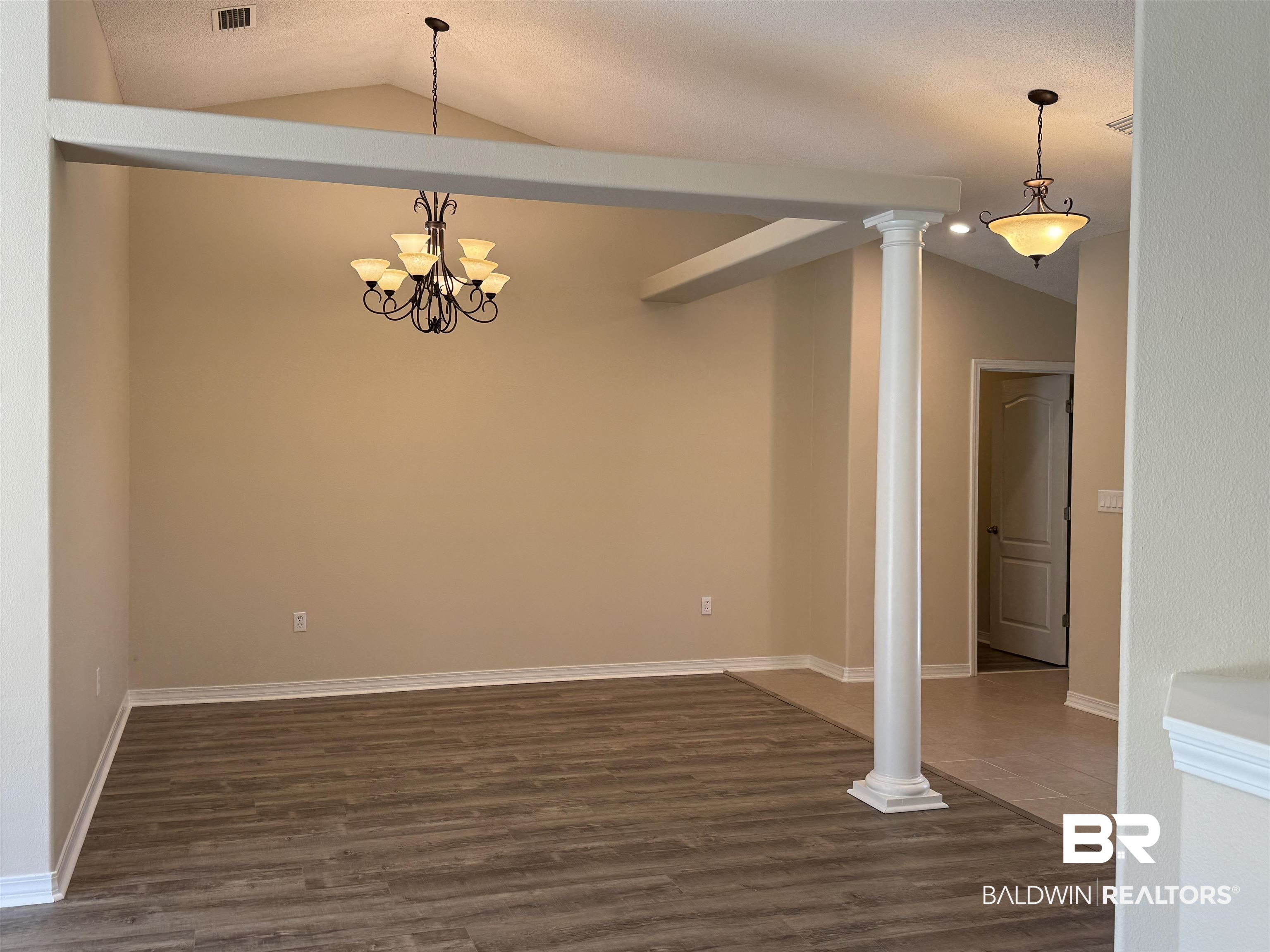 32769 Arbor Ridge Circle Lillian, AL 36549 - Photo 10 of 36 Unfurnished room featuring ornate columns, vaulted ceiling, and dark hardwood / wood-style floors