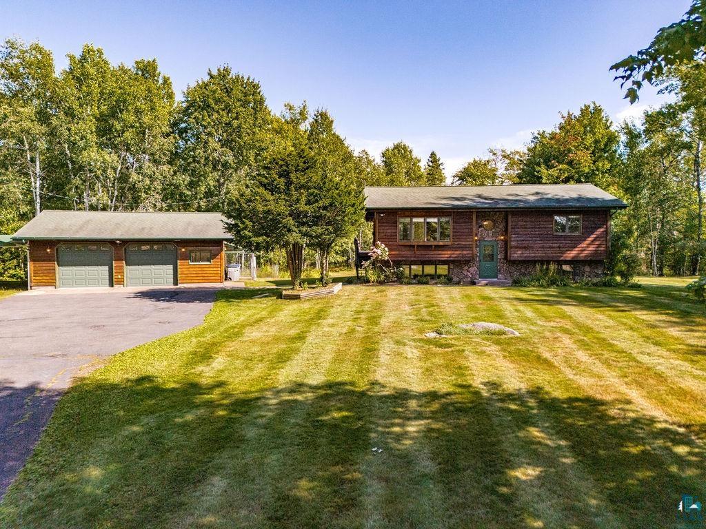 5370 Ugstad Road Hermantown, MN 55811 - Photo 51 of 68 Wood-sided exterior with a stone foundation accent, attached two-car garage, and mature trees
