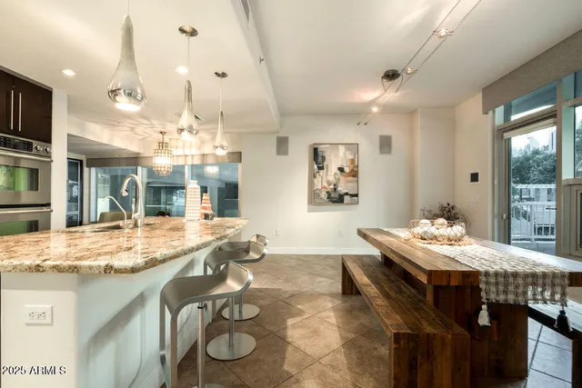 a dining hall with stainless steel appliances granite countertop a stove and a dining table with chairs