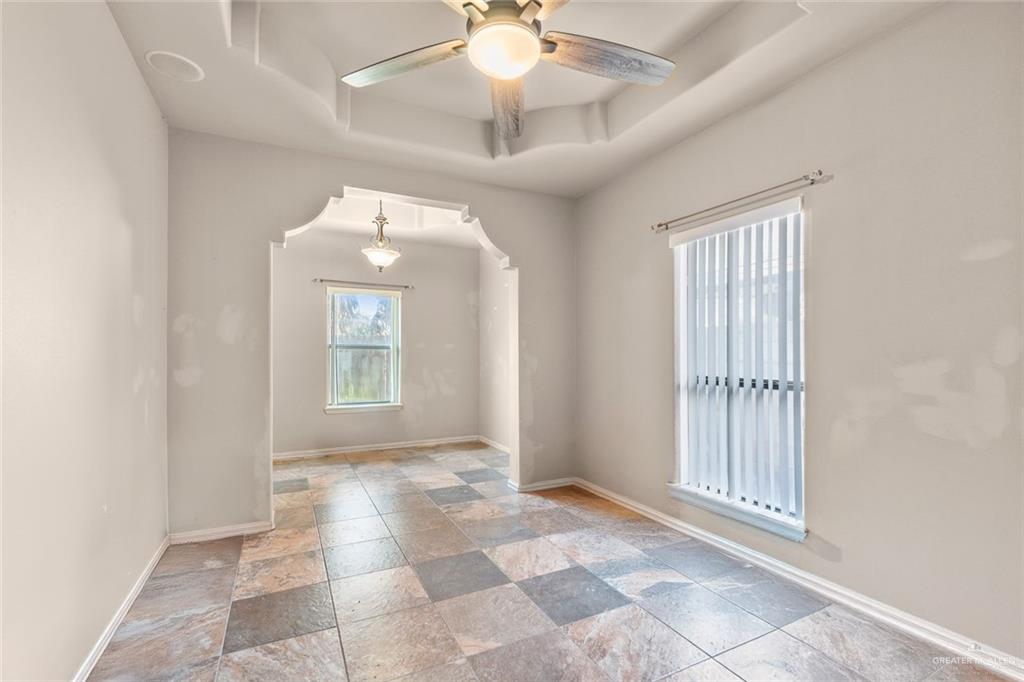2904 Victoria Street Hidalgo, TX 78557 - Photo 17 of 25 Spare room featuring a tray ceiling, a ceiling fan, stone tile floors, and arched walkways