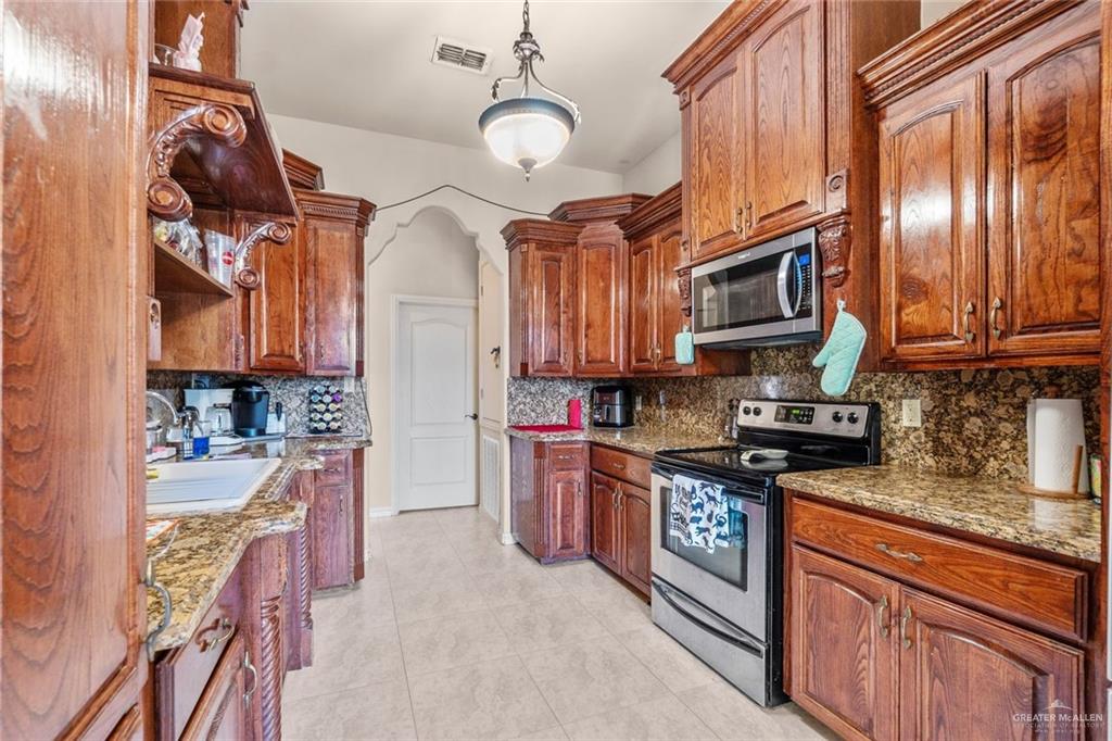 2904 Victoria Street Hidalgo, TX 78557 - Photo 7 of 25 Kitchen with stainless steel appliances, tasteful backsplash, light stone counters, light tile patterned floors, and decorative light fixtures