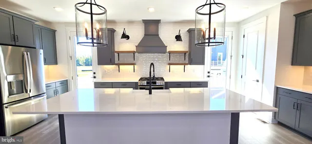 a kitchen with stainless steel appliances a refrigerator a sink and wooden floors