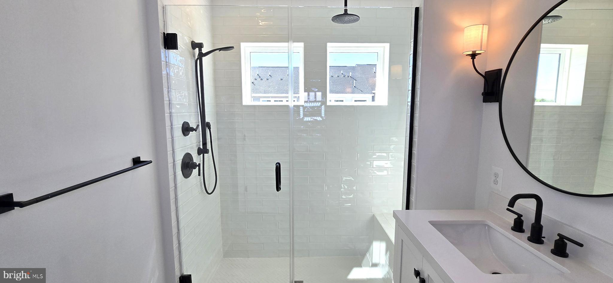 1726 Blacksmith Way Frederick, MD 21702 - Photo 45 of 64 a bathroom with a sink a mirror a vanity and glass door shower