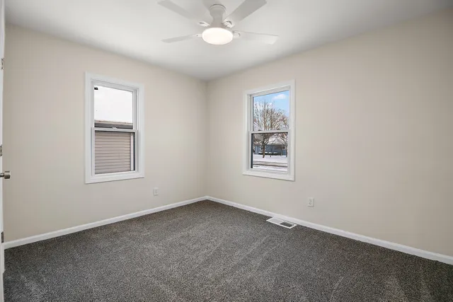 an empty room with a window and a fan