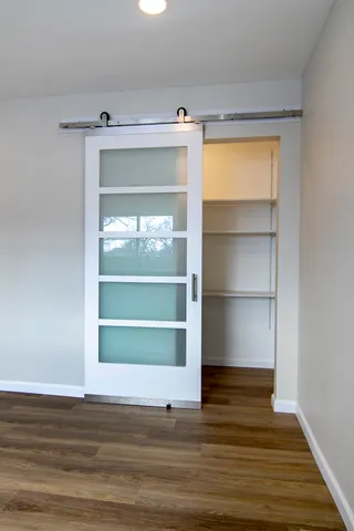 a view of an empty room with a window and wooden floor