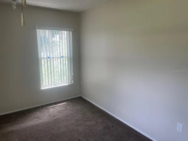 an empty room with chandelier fan and windows