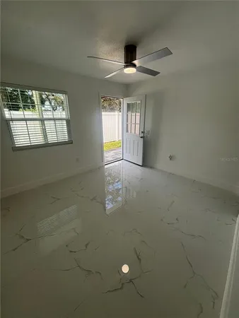 an empty room with windows and ceiling fan