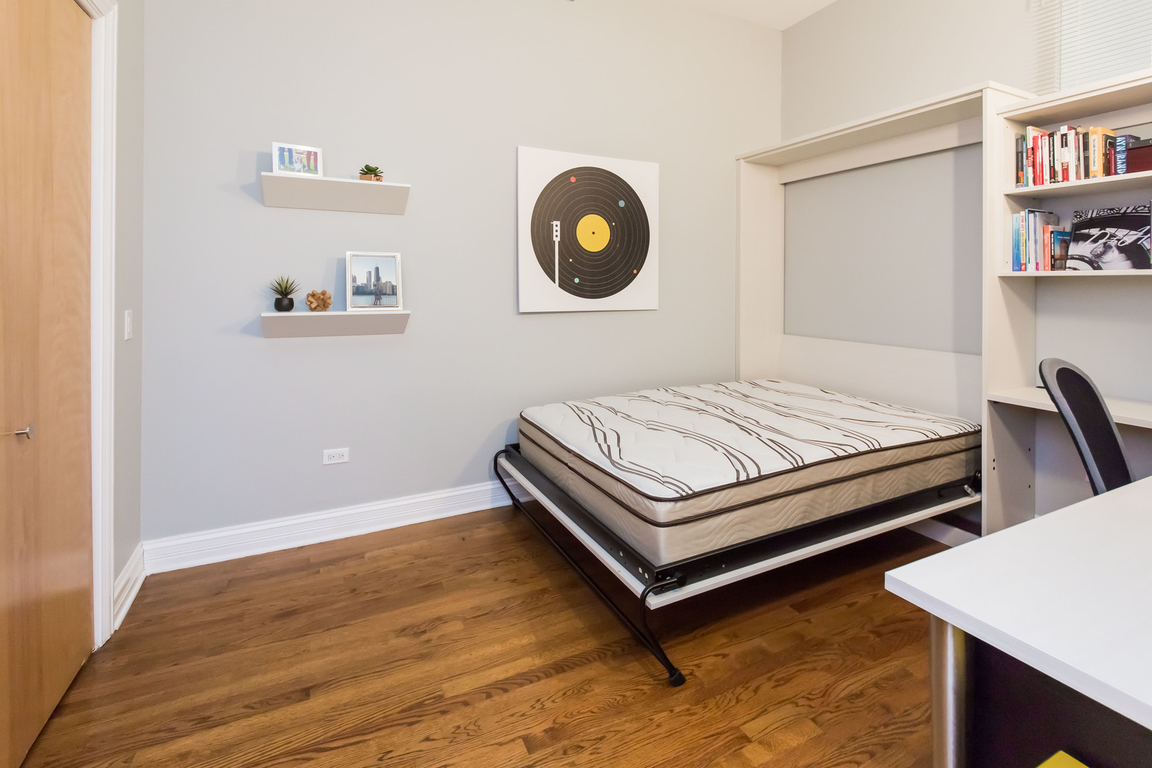 1201 West Adams Street, Unit 705 Chicago, IL 60607 - Photo 21 of 30 a bedroom with a bed and a bookshelf with wooden floor