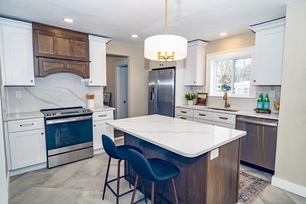 65 Hadwen Road Worcester, MA 01602 - Photo 17 of 38 a kitchen with a stove a sink a kitchen island with chairs and wooden cabinets