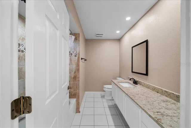 a bathroom with a granite countertop sink a toilet and shower