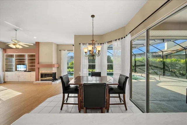 a dining room with wooden floor a chandelier a glass table and chairs