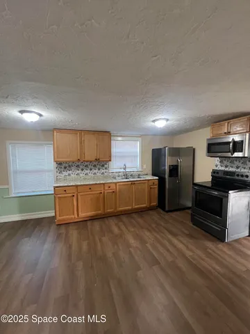 a large kitchen with stainless steel appliances kitchen island a large counter top and a stove top oven