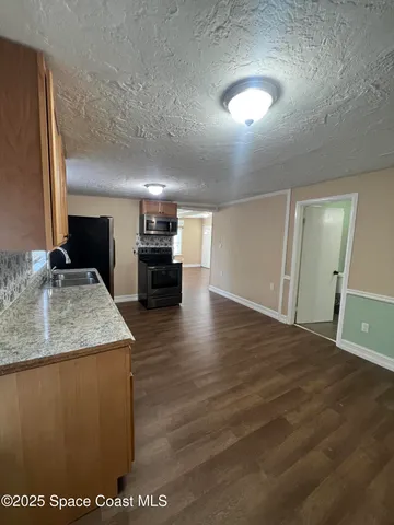 a view of kitchen island kitchen with granite countertop refrigerator stove dining table and chairs