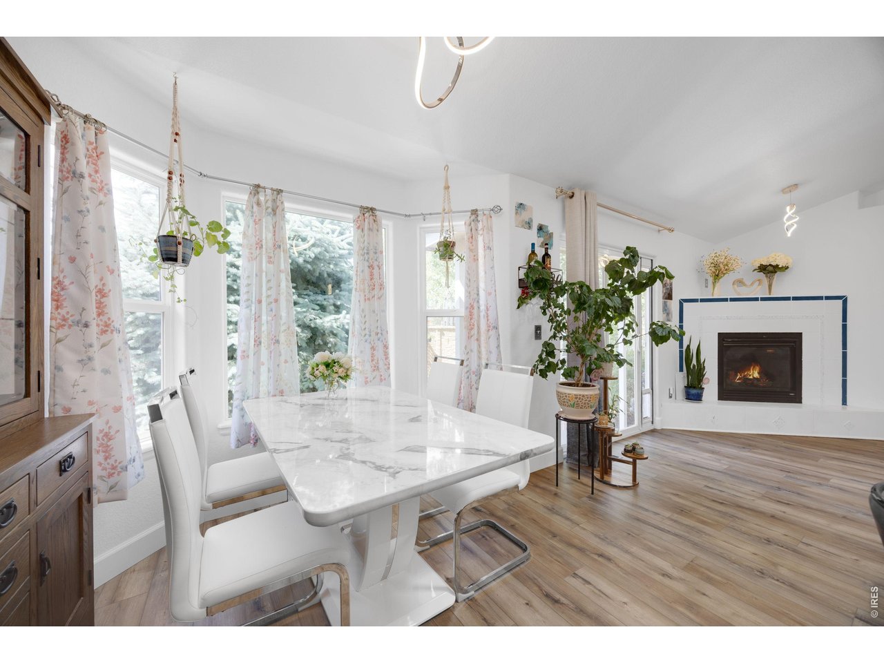 148 Beacon Way Windsor, CO 80550 - Photo 10 of 36 Bright dining area with large windows, updated flooring, modern lighting, and an open layout flowing seamlessly into the living room with a cozy gas fireplace and backyard access.