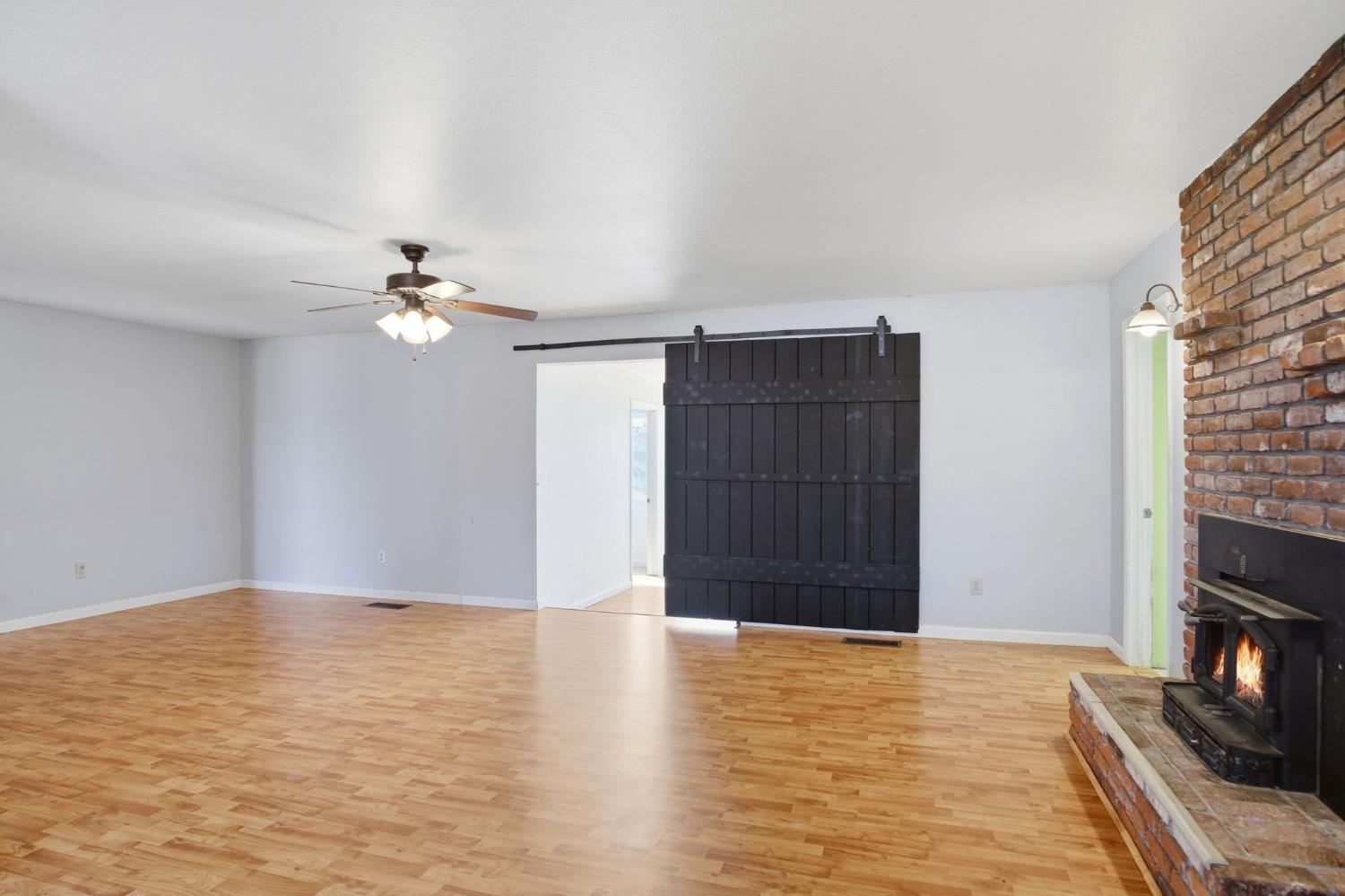 1409 Stonum Road Modesto, CA 95351 - Photo 8 of 40 a view of an empty room with wooden floor and a fireplace