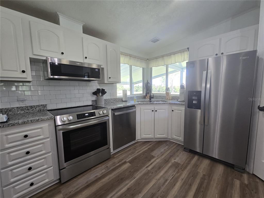 3935 Parway Road, Unit 1322 Zellwood, FL 32798 - Photo 6 of 28 a kitchen with stainless steel appliances white cabinets and a stove top oven