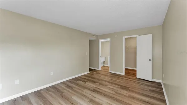 a view of an empty room with wooden floor and closet
