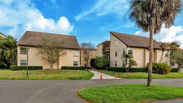 a view of a white house with a big yard and palm trees