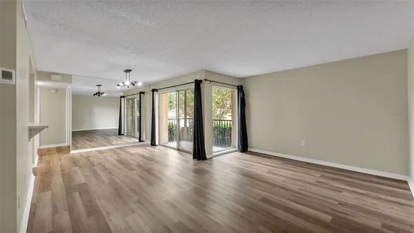 a view of an empty room with window and wooden floor