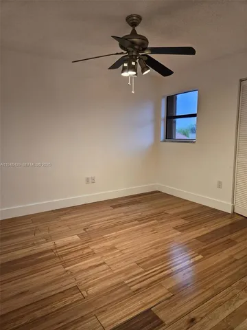 a view of a room with wooden floor and a ceiling fan