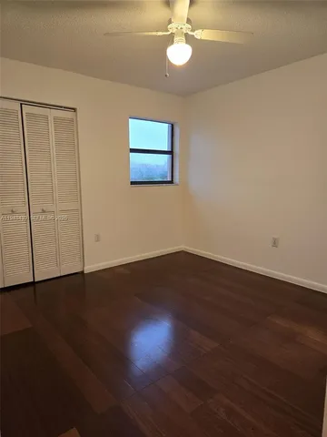 an empty room with wooden floor fan and window