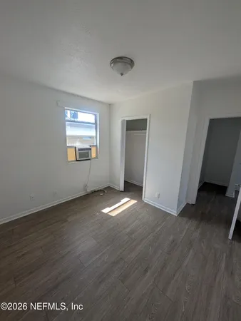 a view of empty room with wooden floor and fan