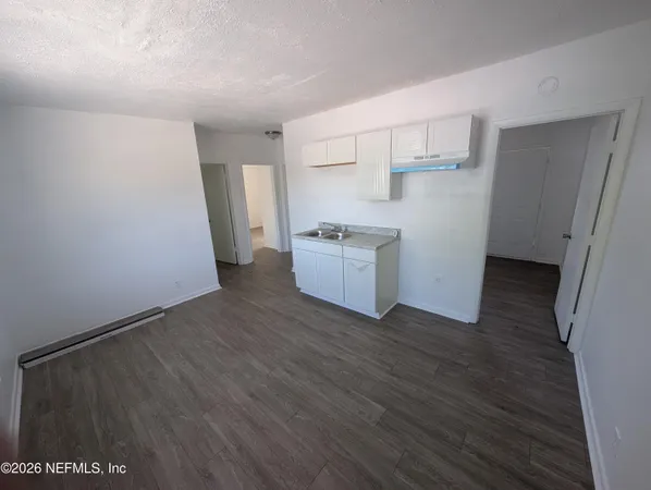 a view of a kitchen with a sink stove cabinets and empty room