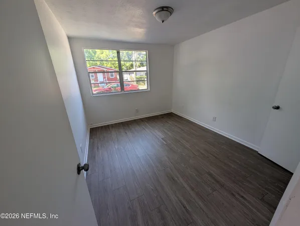 an empty room with wooden floor and windows