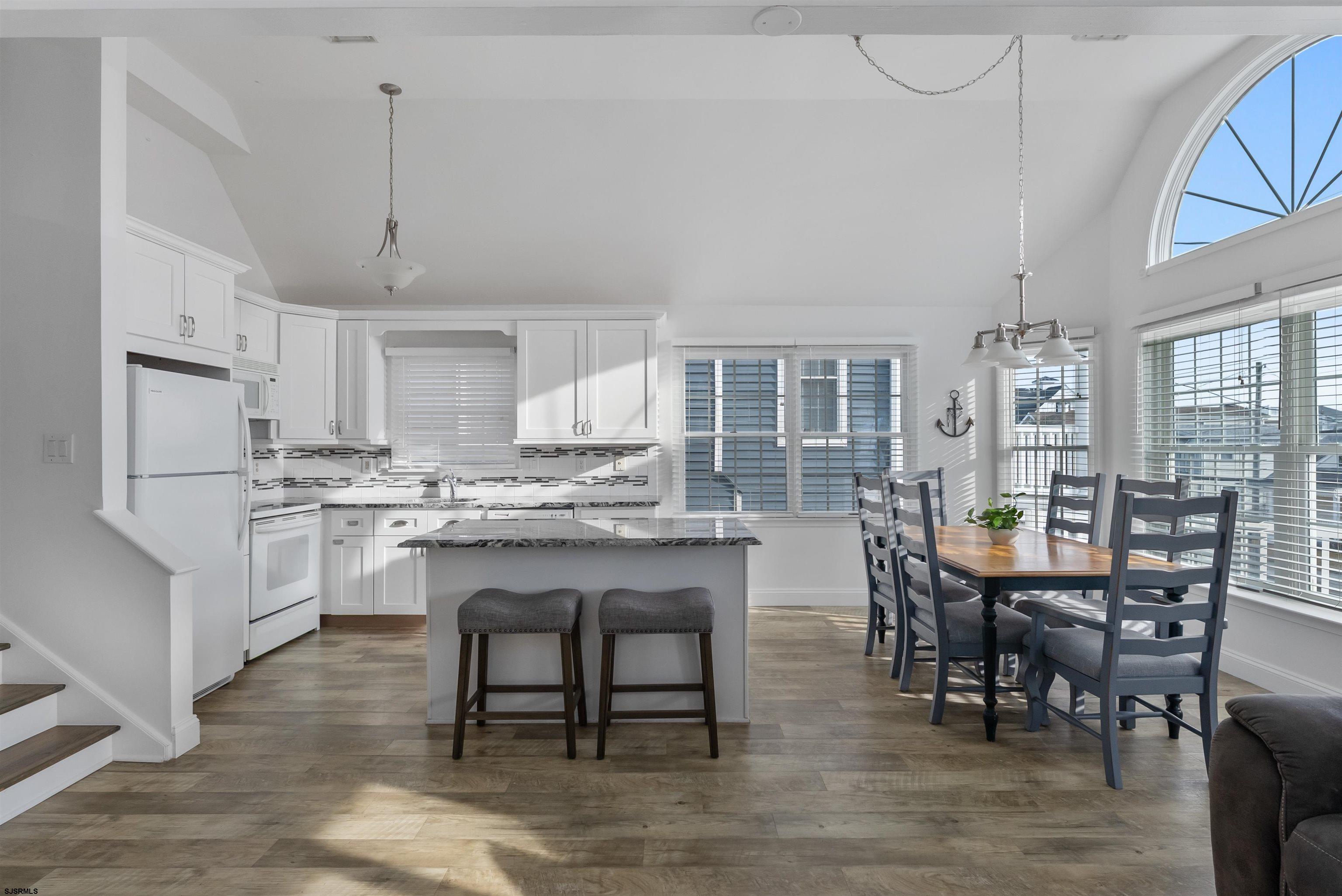 4930 Asbury Avenue, Unit 2 Ocean City, NJ 08226 - Photo 6 of 25 a kitchen with stainless steel appliances granite countertop a table chairs wooden floors a stove and white cabinets