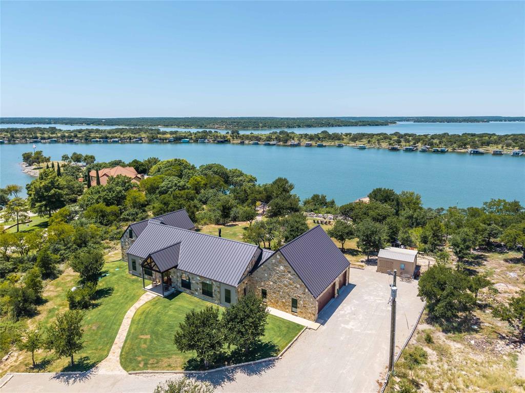 1005 Deep Water Road May, TX 76857 - Photo 3 of 40 Stone exterior residence with a dark metal roof, set on a landscaped lot with mature trees