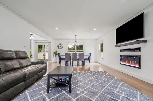 a living room with furniture a flat screen tv and kitchen view