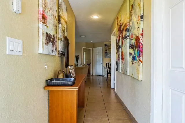 a hallway with painting on the wall and a potted plant