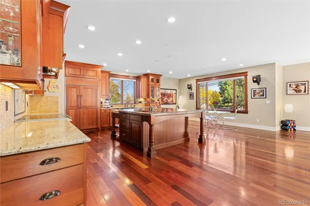 a kitchen with stainless steel appliances granite countertop a stove a sink dishwasher and a refrigerator with wooden floor