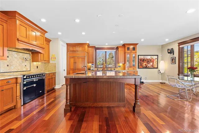 a large kitchen with stainless steel appliances granite countertop a large center island and a wooden floors