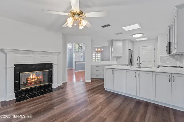 a open kitchen with a fireplace and wooden floor