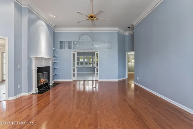 an empty room with wooden floor fireplace and windows