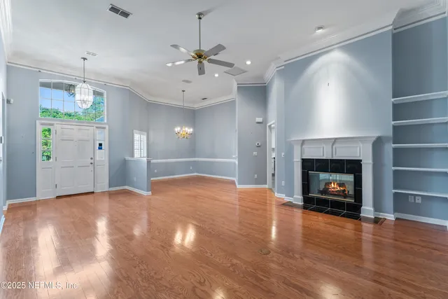 a view of an empty room with wooden floor fireplace and a window