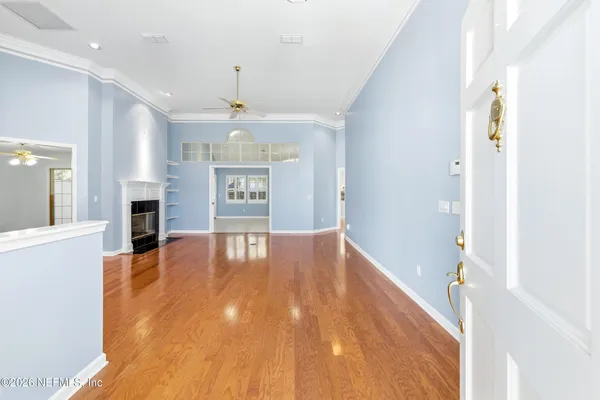 a view of empty room with wooden floor and fan