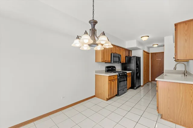 a large kitchen with stainless steel appliances granite countertop a sink a stove top oven and a chandelier