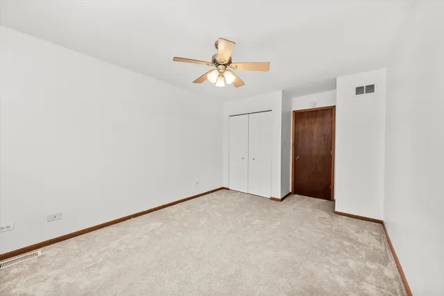 an empty room with closet and a chandelier fan