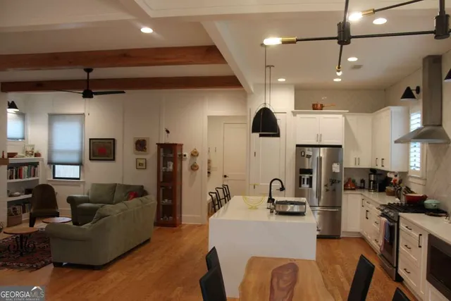 a living room with stainless steel appliances furniture a fireplace a flat screen tv and a view of kitchen