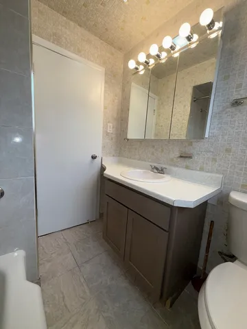 a bathroom with a sink vanity mirror and toilet