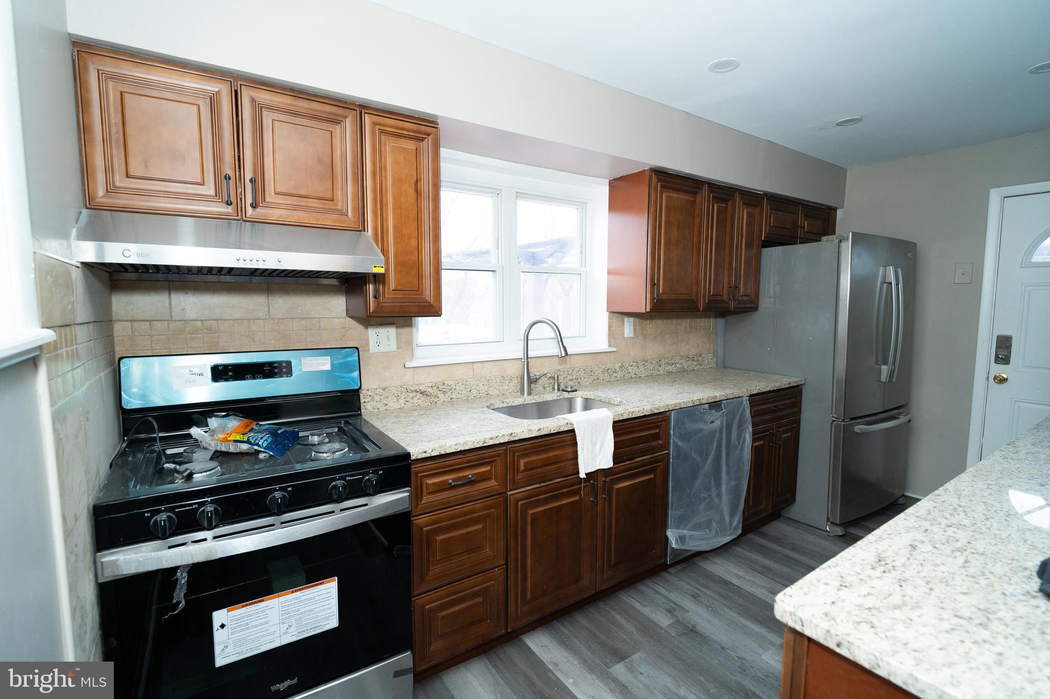 7209 Hazel Avenue Upper Darby, PA 19082 - Photo 7 of 35 a kitchen with stainless steel appliances wooden cabinets and a stove top oven