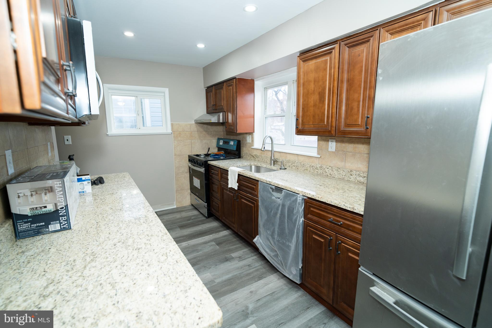 7209 Hazel Avenue Upper Darby, PA 19082 - Photo 8 of 35 a large kitchen with stainless steel appliances granite countertop a stove a sink dishwasher and a refrigerator with wooden floor