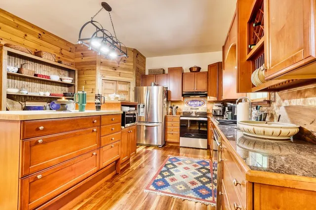 a kitchen view with stainless steel appliances granite countertop a stove and more cabinets