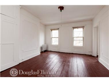 a view of an empty room with wooden floor and window