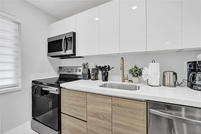 a kitchen with white cabinets a sink and a stove