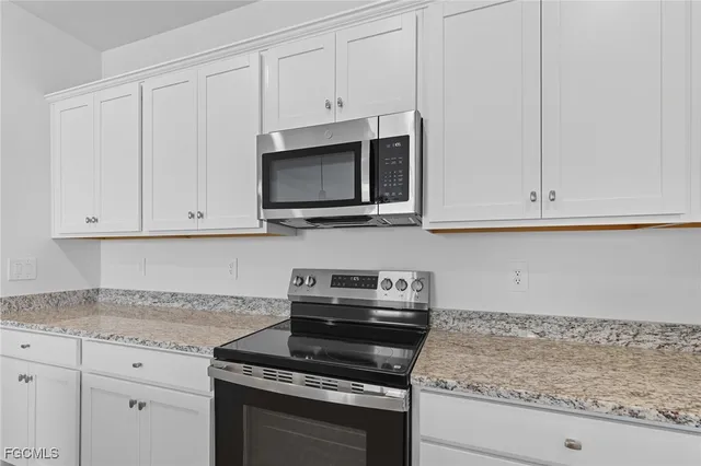 a kitchen with granite countertop white cabinets and a stove top oven